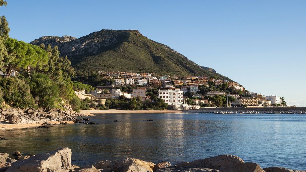 Veduta di una spiaggia con una città costiera ai piedi di una montagna