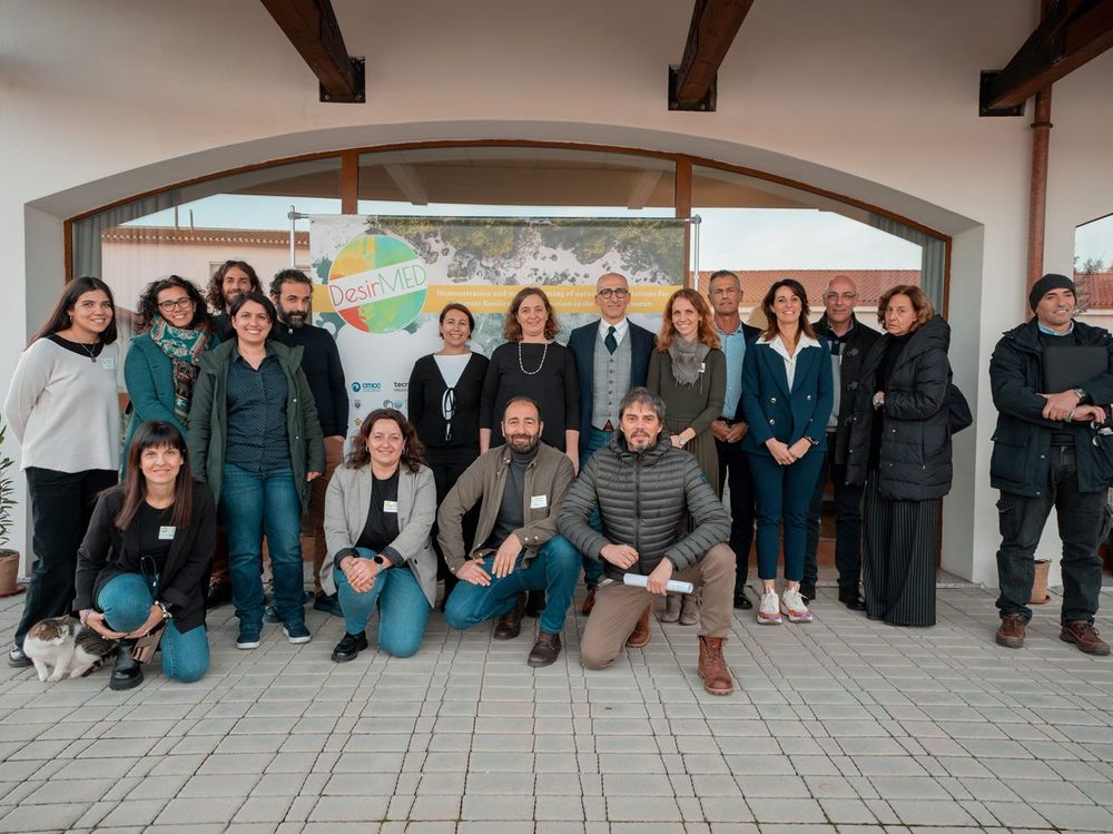 Gruppo di persone in piedi e inginocchiate davanti a un grande striscione con il logo 'DesirIMED'.