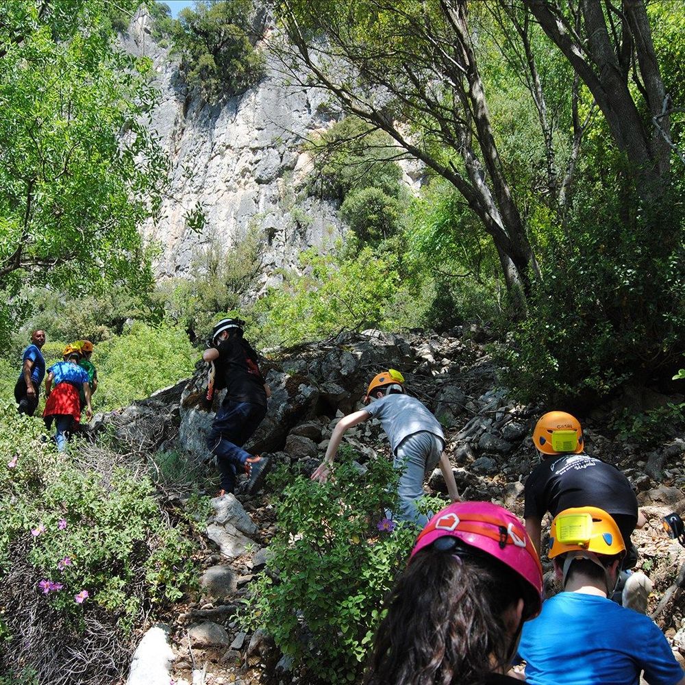 Gruppo di persone con caschi da arrampicata su sentiero roccioso in ambiente naturale