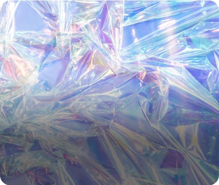 Una plastica trasparente iridescente spiegazzata con riflessi di luce che creano sfumature di colore blu, rosa e viola